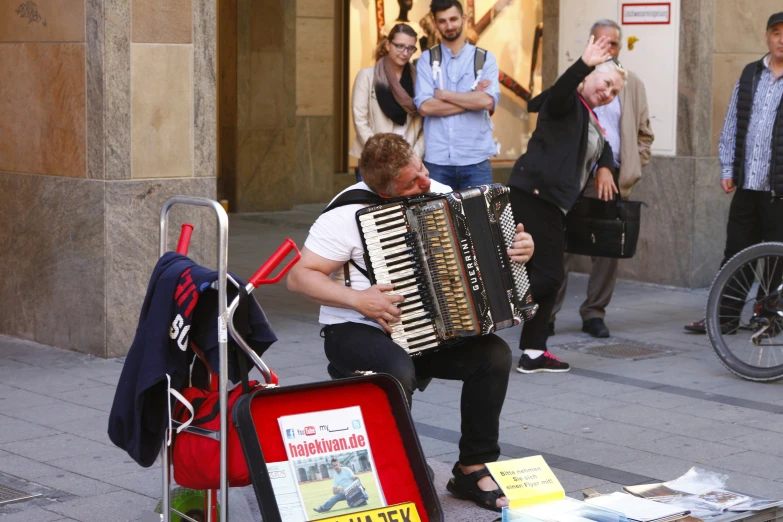 a man sitting on a street corner playing an accordion