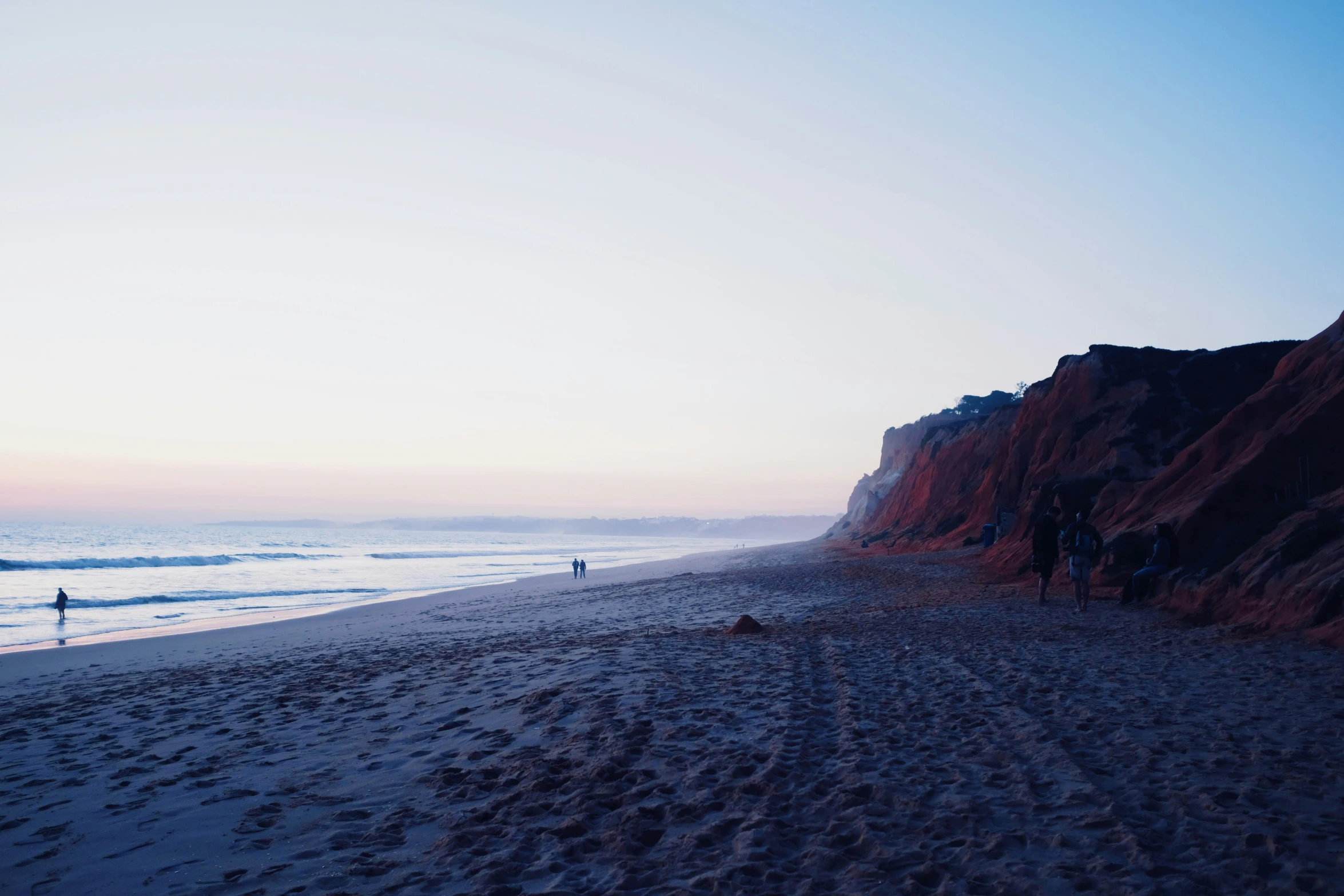 a beach with people walking on the shore line