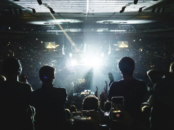 people are seated in a darkened room while someone sings