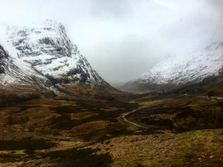 a mountain with a road in the middle and snow on the top