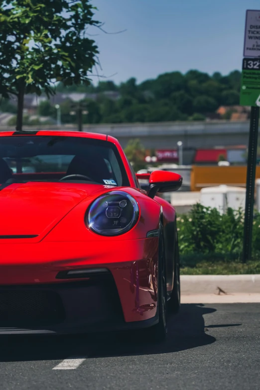 red car driving down street during daytime near street sign