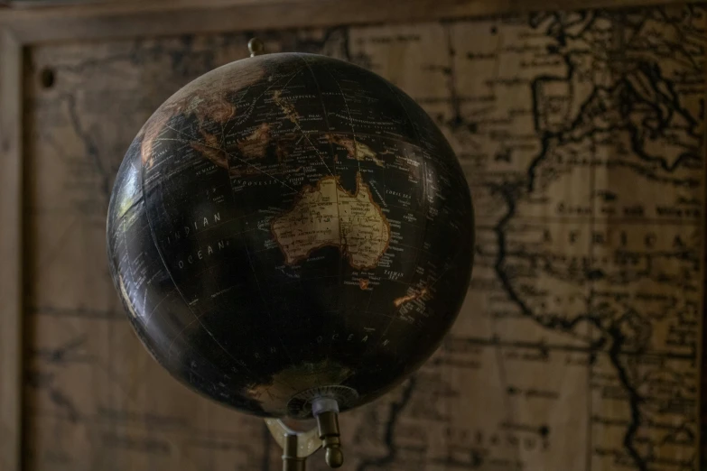 an old, dark black - and - gold looking, globe is placed on top of a wall
