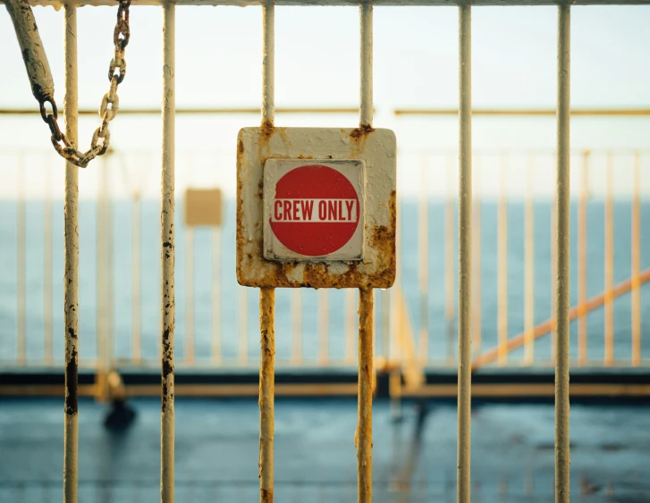 an old rusted sign sitting behind a gate that is locked