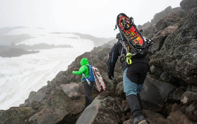 two people with ski equipment on a rocky hill