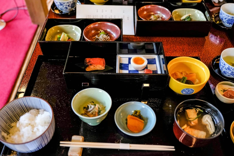bowls of food sit on a tray near chop sticks