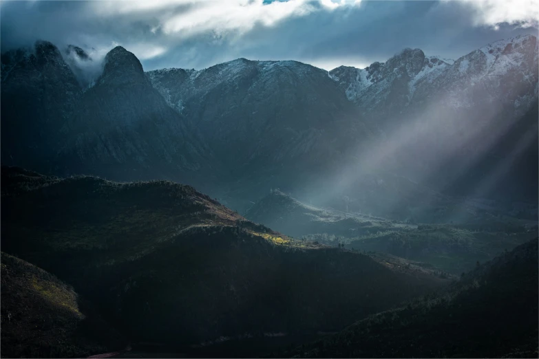 a group of mountains in the distance with sunlight shining from behind