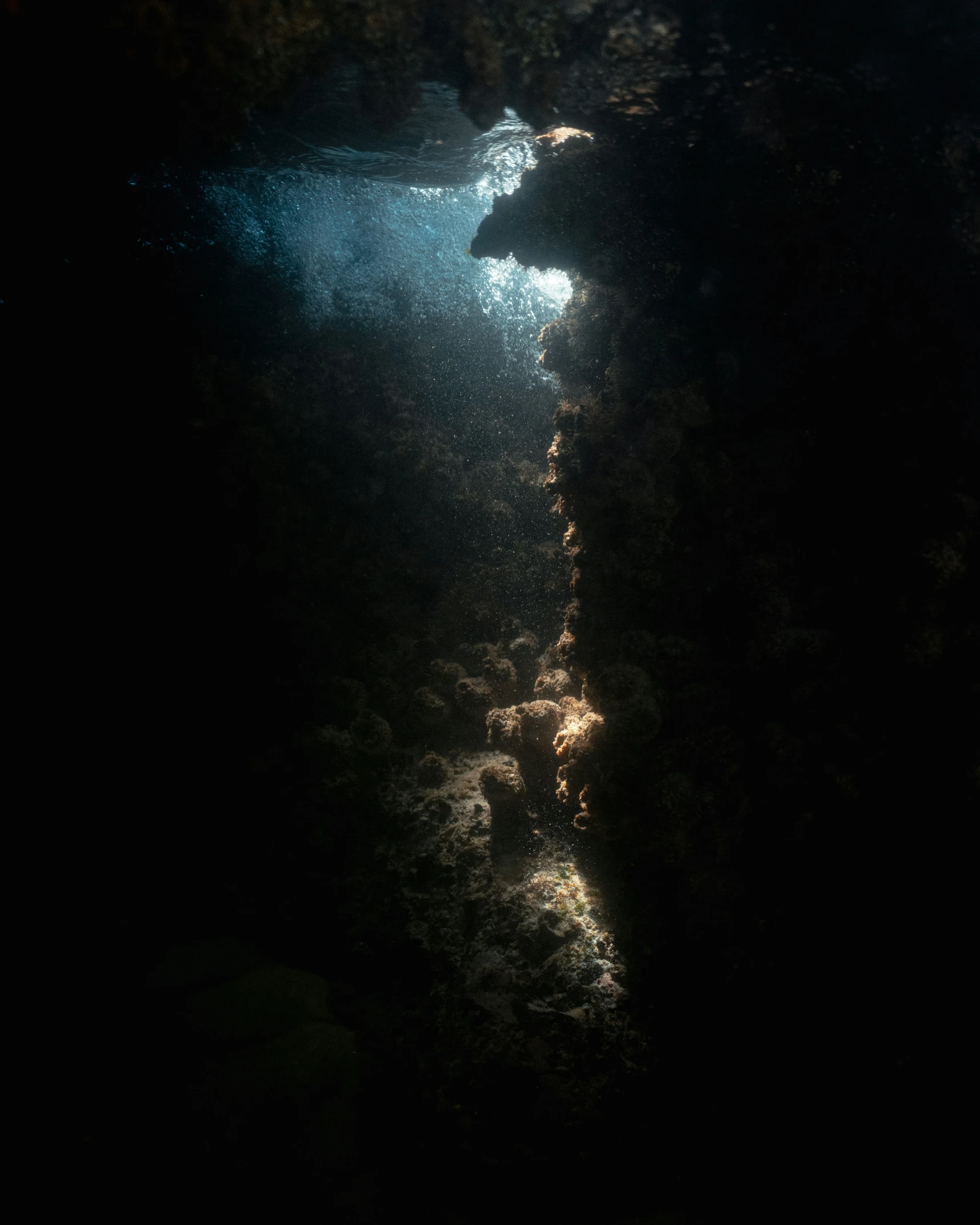 a deep underwater tunnel with the light from a scuba light