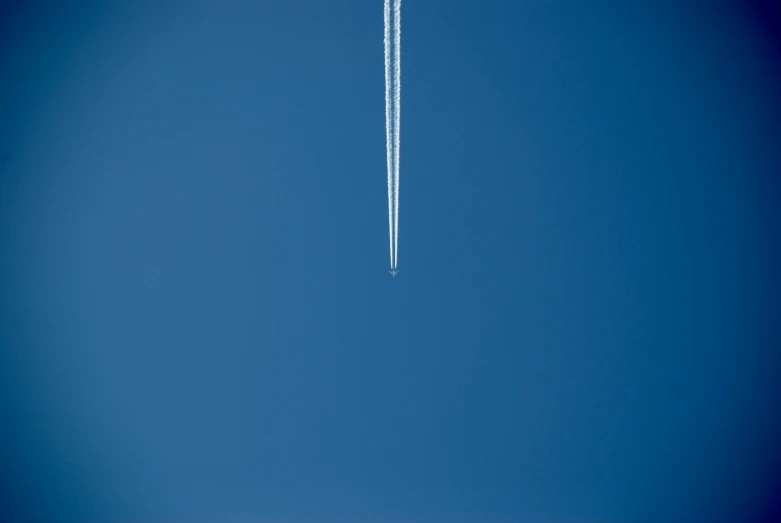 a contrail flies high in the sky over the ground