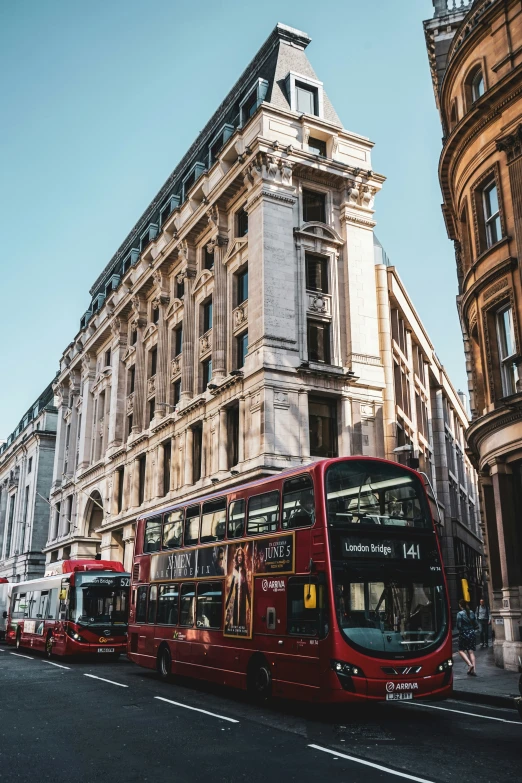 three red double decker buses are parked outside of an old building