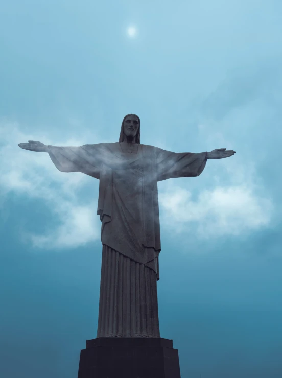 the statue has its arm spread wide open in front of a blue sky