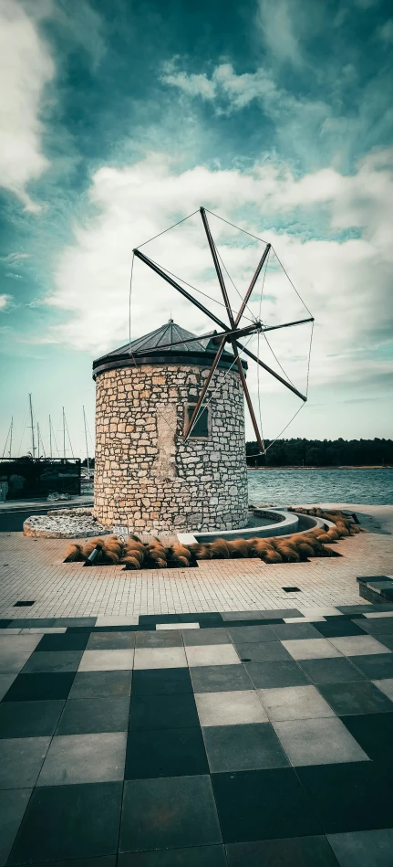 an old windmill stands alone on the shore of a lake