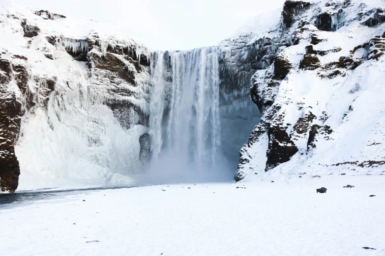 a man that is standing in the snow near some water