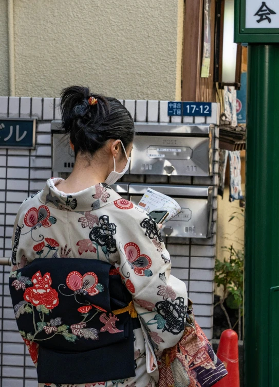 a woman in a kimono getting mail from the street