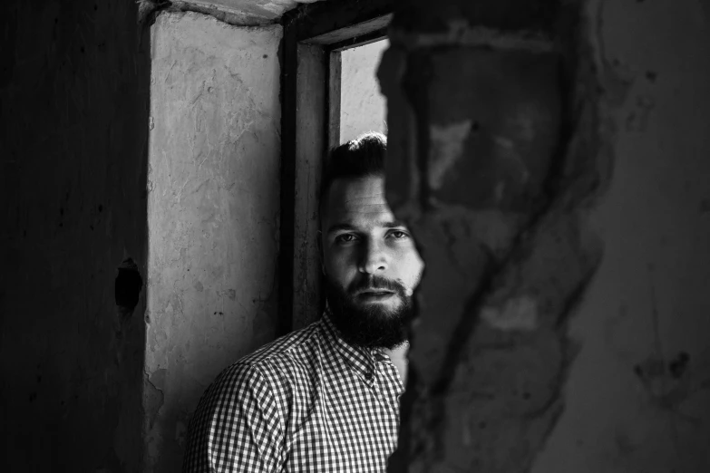 man standing next to window in brick building