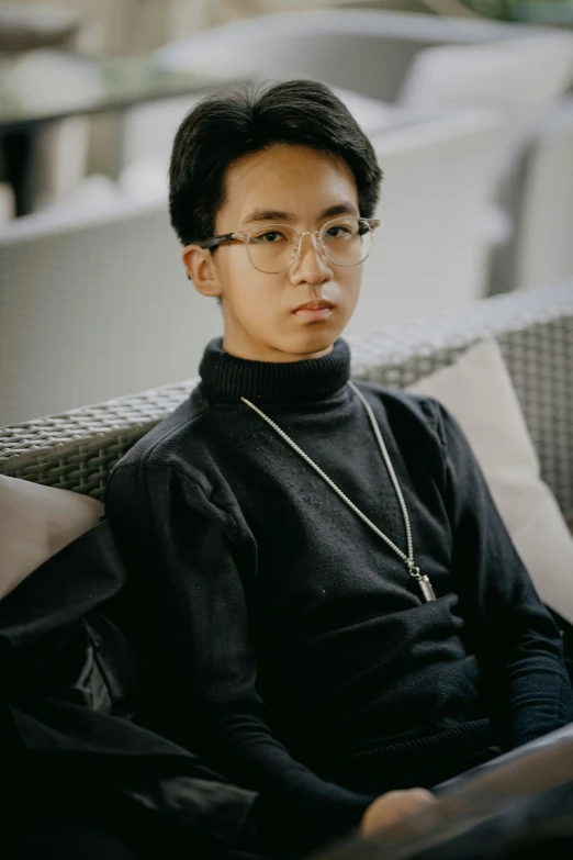 a young asian male with glasses on a chair