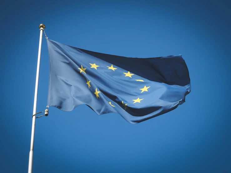 an american and eu flag are flying on top of a pole