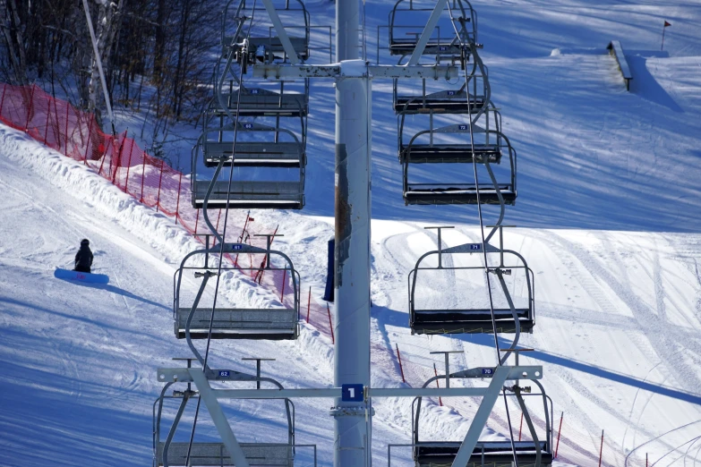 a person sits on a snowboard next to the chairlift