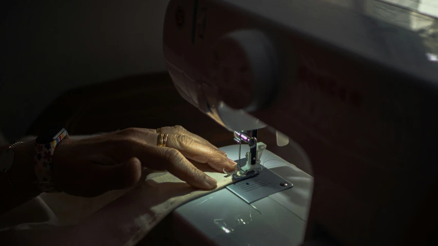 a person with an electronic device at the sewing table