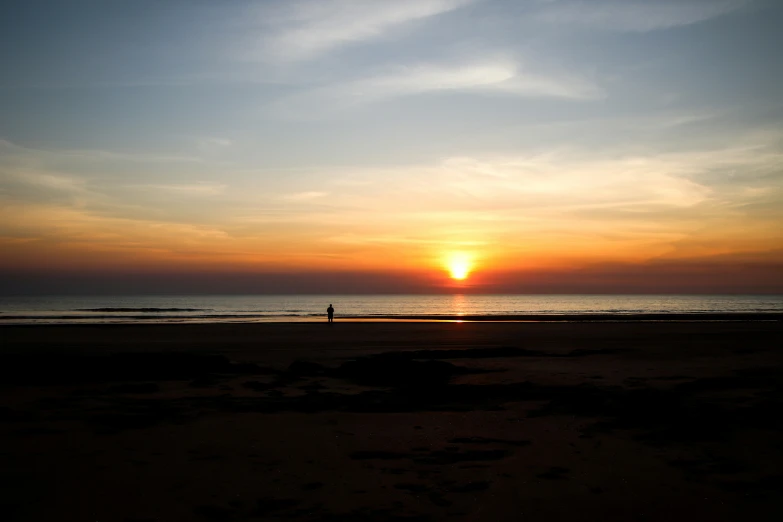 a person standing on the beach at sunset