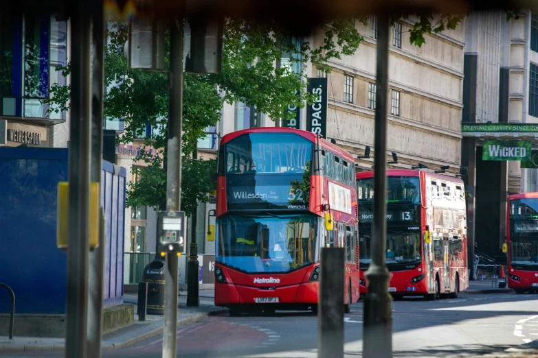 three red buses are parked next to each other in the city