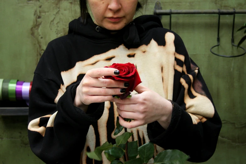 a woman wearing a black and white striped jacket holding a red rose