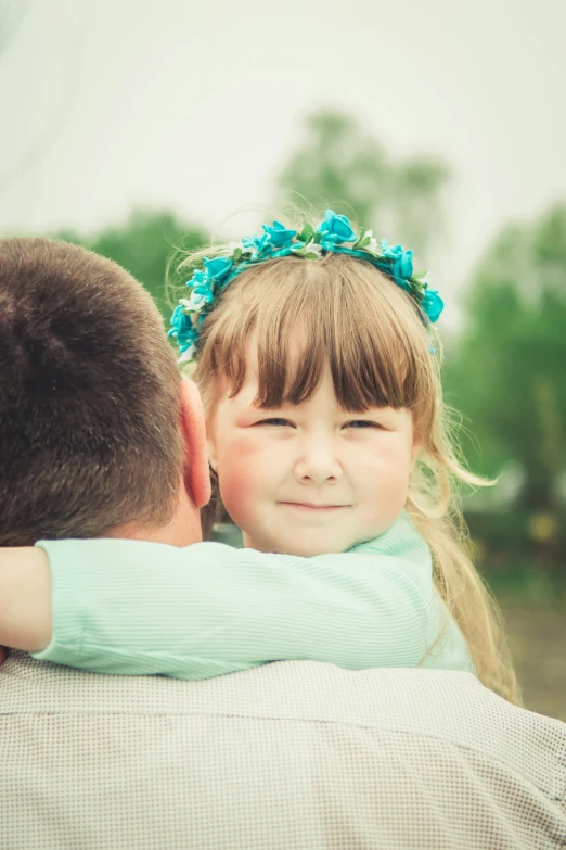 a little girl in her father's arms looks up and smiles