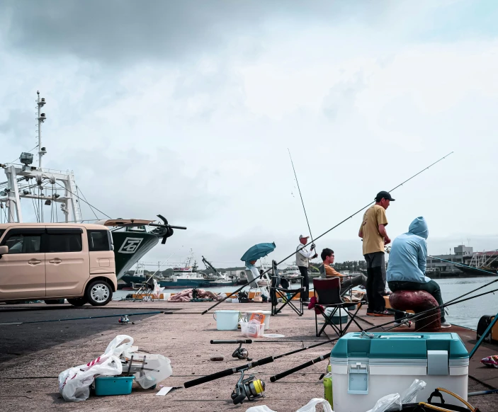 several people are fishing on a dock while an suv is parked nearby