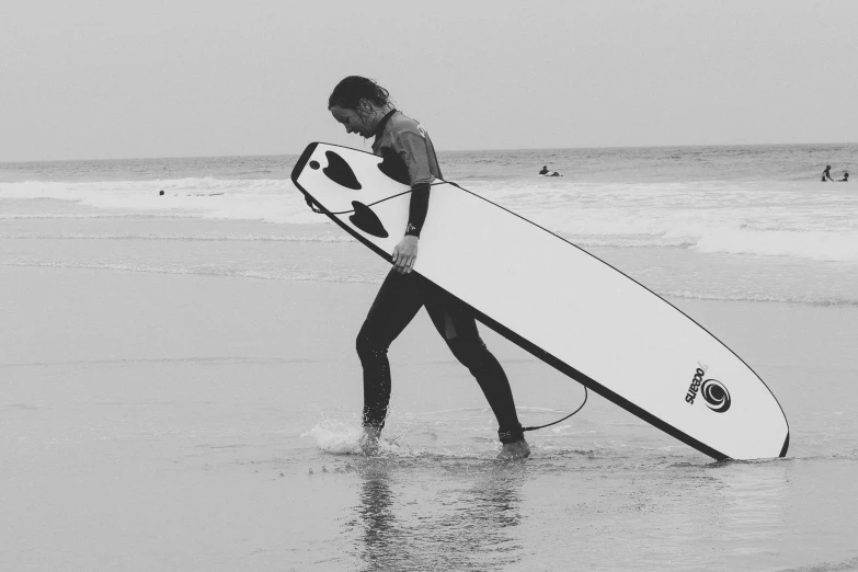 black and white pograph of a person carrying a surfboard