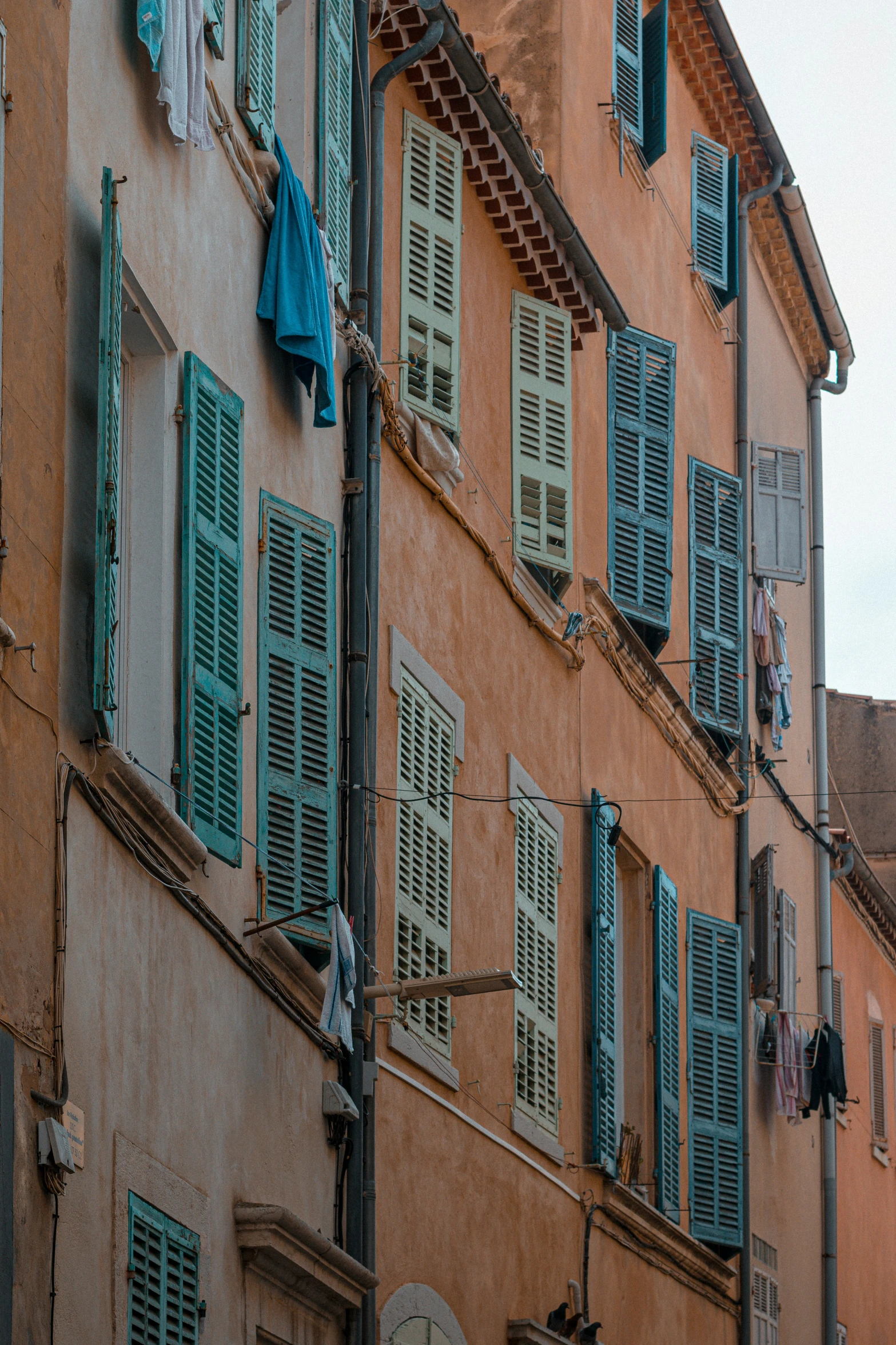 an old pink colored building with green shutters