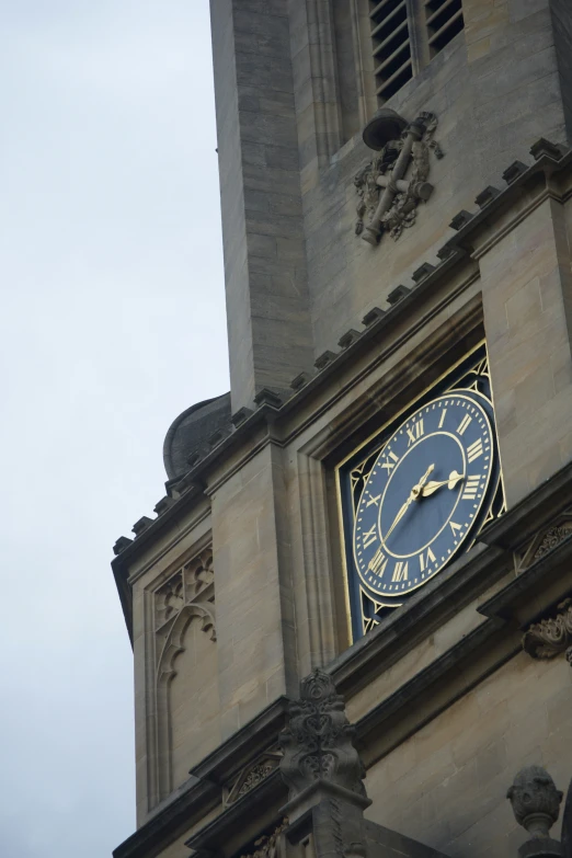 a blue clock on a stone building in front of sky