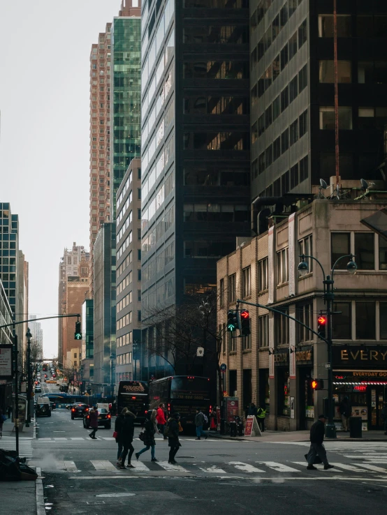 people are walking across a city street near a light pole