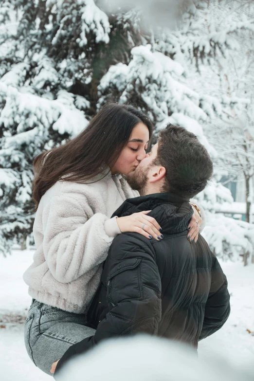 a young couple kissing while sitting in the snow