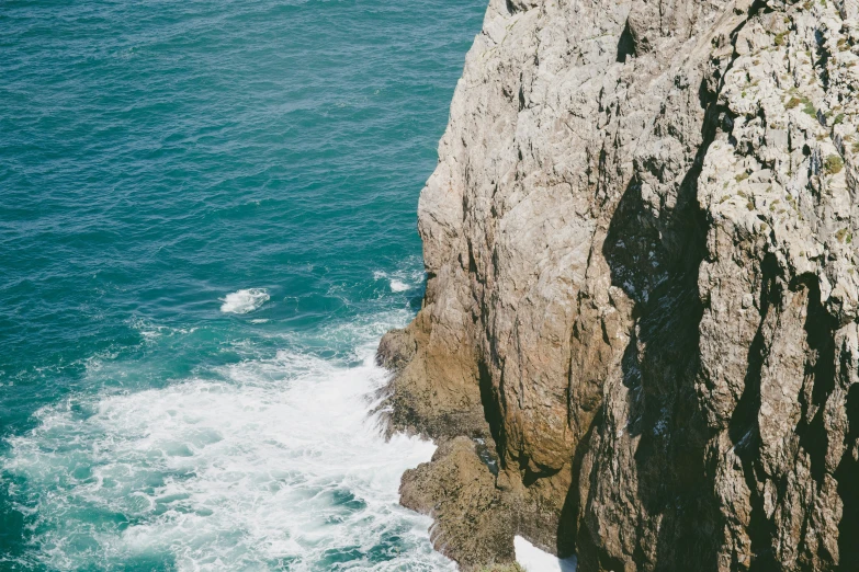 a view of a large body of water next to a rocky cliff