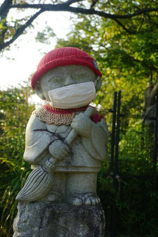 a statue of a person wearing a red hat and holding a broken cigarette