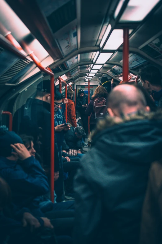 people on a crowded train looking at their cell phones