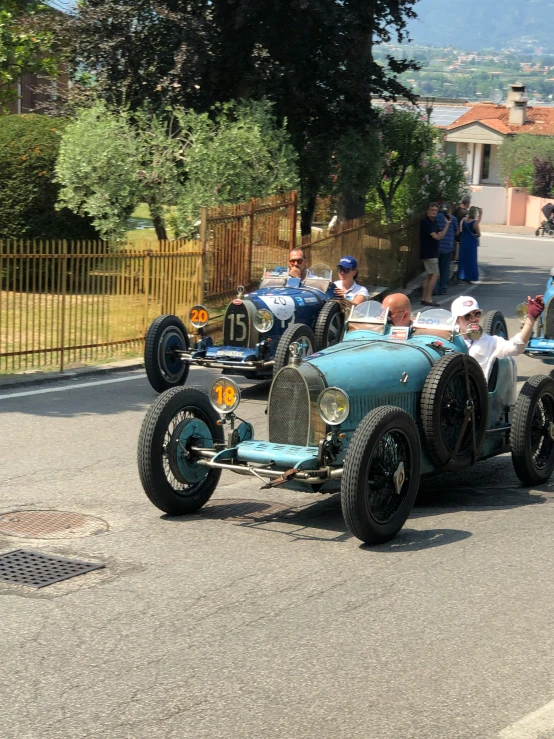 some vintage race cars going down the road