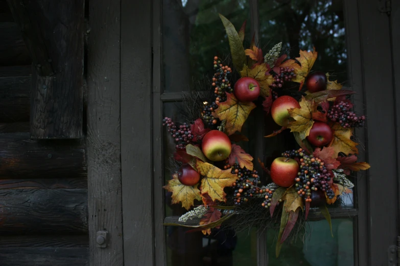 the wreath is set in front of an open window with leaves, apples and berries