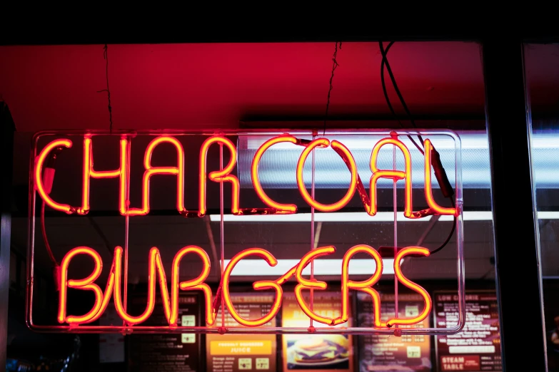 a lighted sign that reads, charcoal burgers