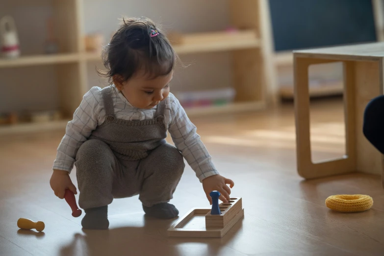 baby playing with wooden toy in playroom with furniture