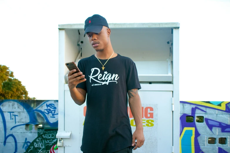 man holding cell phone by truck with graffiti on the wall