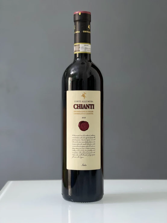 a bottle of wine on a counter in front of a gray wall