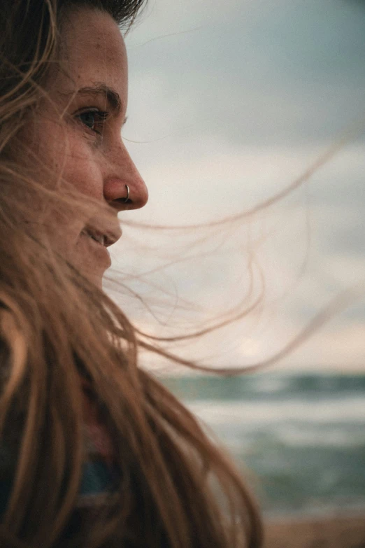 a close up po of the head of a young woman with her hair blowing in the wind