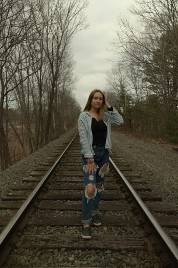 a woman stands on a railroad track and holds her hand on the rail