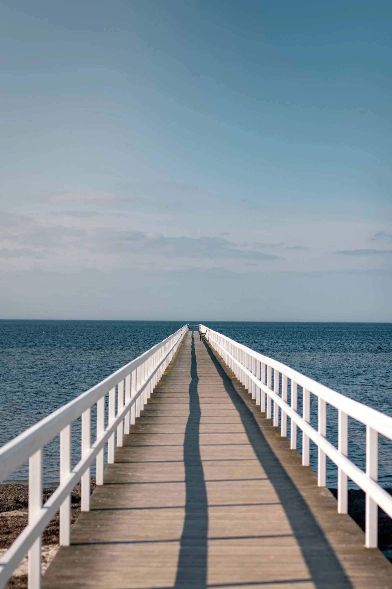 a person is walking on the pier towards the ocean