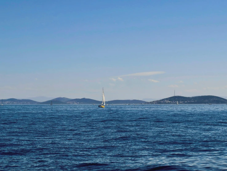 a small sailboat sails through the blue water