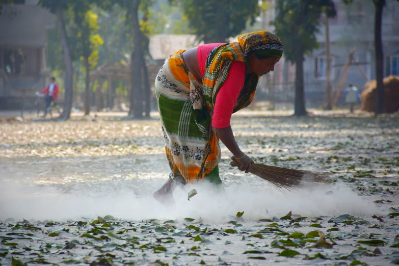 a woman is spreading the leaves in a plaza