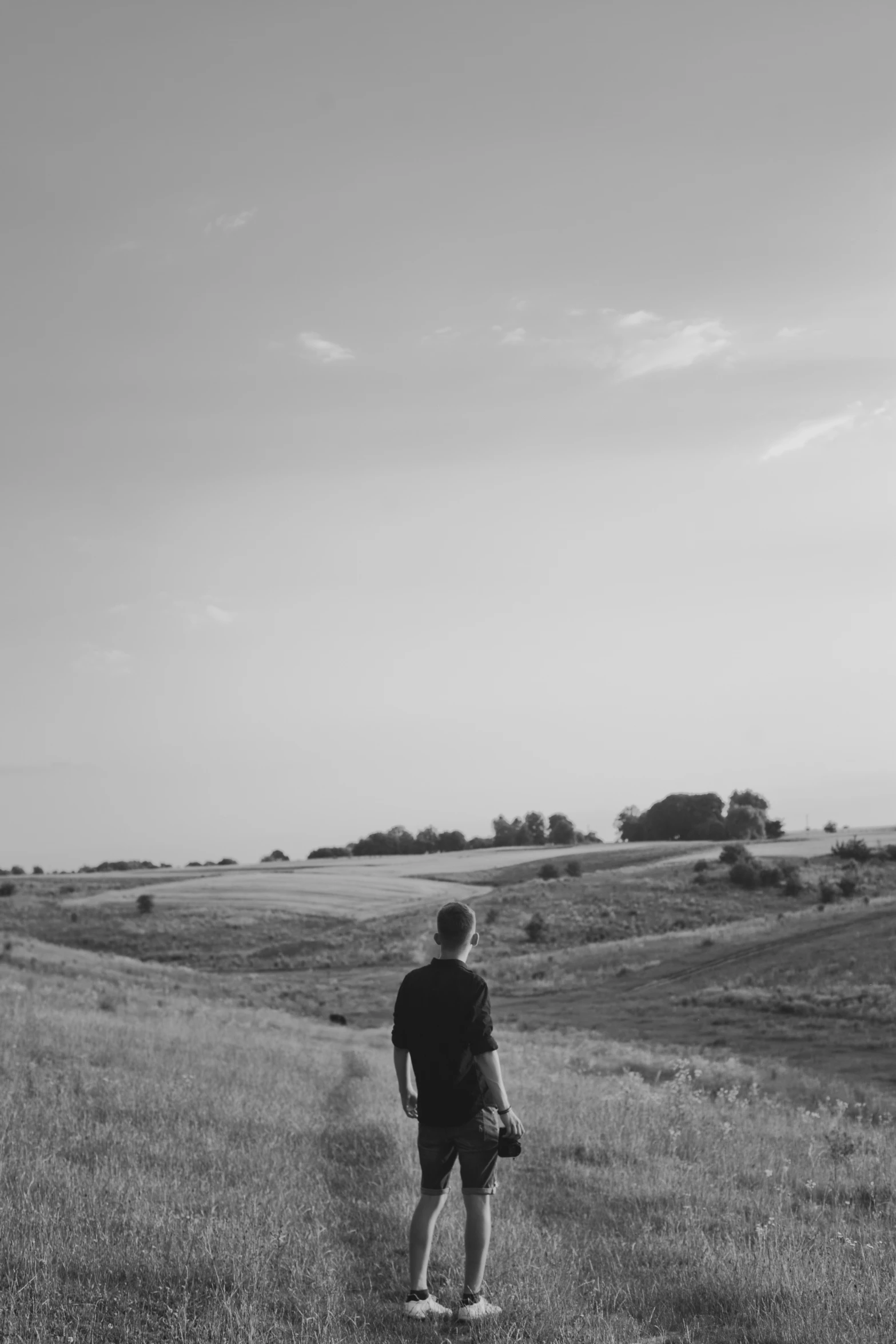 a person walking away from the camera toward a wide open field