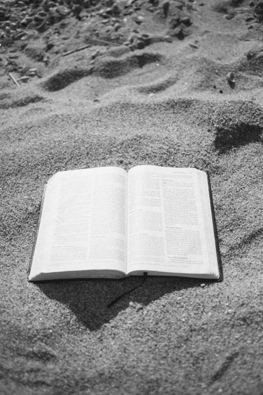 an open book sits on the beach sand