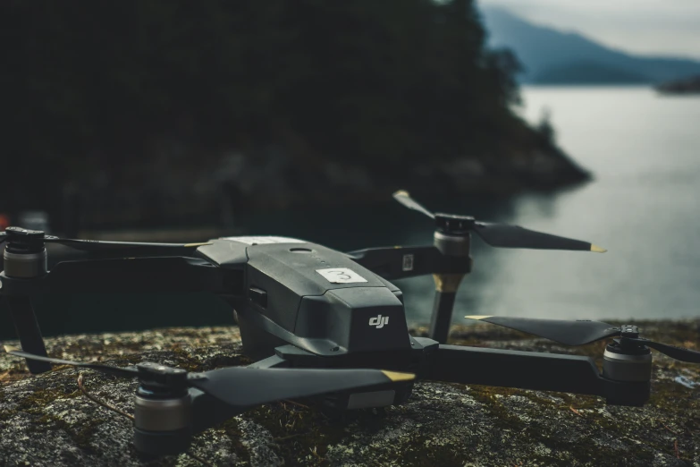 a small grey and black remote controlled airplane flying over a body of water