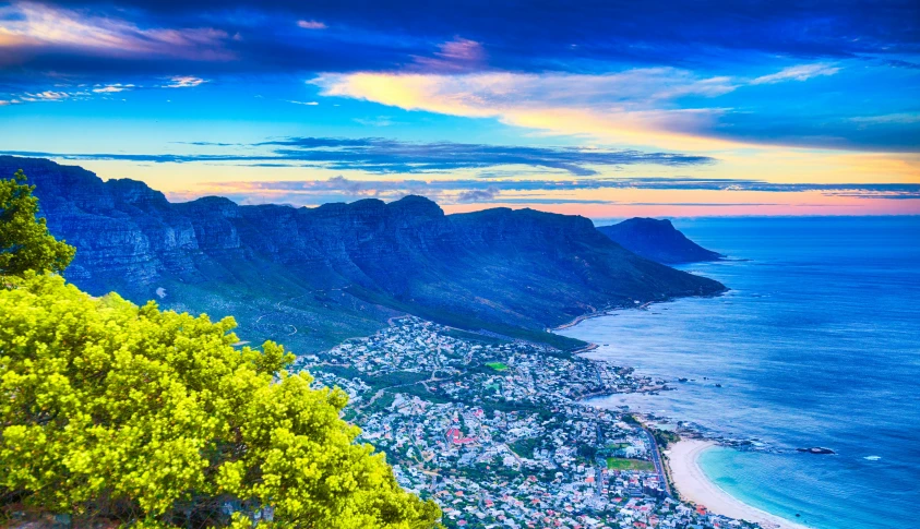 the ocean and mountains with some clouds above it